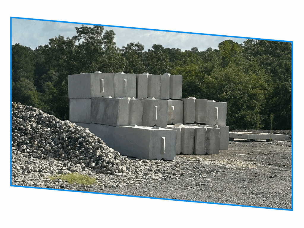 Large concrete blocks stacked outdoors near a pile of gravel, with trees in the background.
